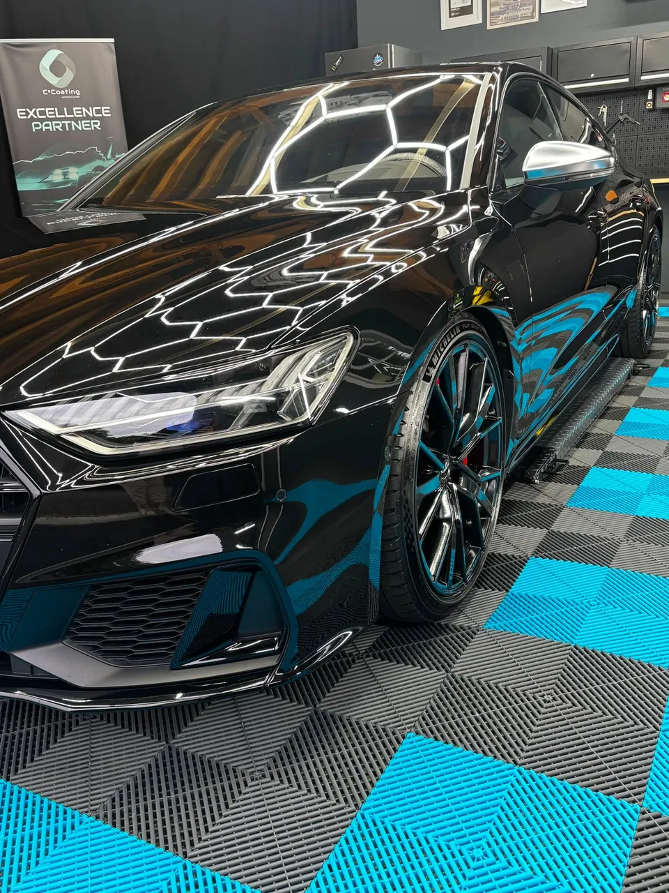 Zwei aufbereitete Fahrzeuge in Werkstatt mit C+Coating Excellence Partner Logo und Cyan-Akzenten
